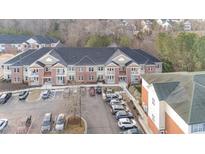 Apartment building featuring brick and siding, balconies, parking lot and professional landscaping at 411 Weather Ridge Ln # 45, Cary, NC 27513