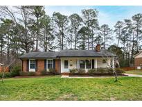 Charming one-story brick home with a well-maintained lawn and mature trees at 5920 North Hills Dr, Raleigh, NC 27609