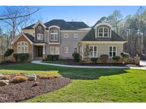 Beautiful two-story brick home with manicured lawn and a mix of stone and wood facade accents at 65 Gentle Winds Dr, Chapel Hill, NC 27517