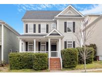 Charming two-story home with a well-manicured lawn, classic windows and black shutters under a partly cloudy sky at 909 Edgewater Cir, Chapel Hill, NC 27516