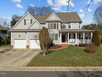 Charming home with a well-manicured front yard, attached garage, and inviting front porch with classic white pillars at 100 Maywood Way, Chapel Hill, NC 27516