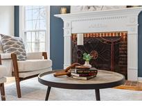 Living room features a fireplace with decorative mantle and round coffee table with decor at 112 Parkmeadow Dr, Cary, NC 27519
