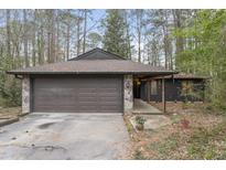 Charming single-story home featuring a stone-accented facade, brown garage door and wooded surroundings at 118 Flora Mcdonald Ln, Cary, NC 27511