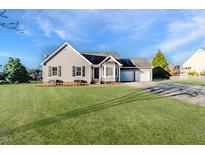 Charming single-story home with a well-manicured lawn and attached two-car garage at 1304 Trotter Bluffs Dr, Holly Springs, NC 27540