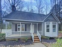 Charming gray home featuring a cozy porch with white railings and a beautifully landscaped front yard at 205 Dwelling Pl, Knightdale, NC 27545