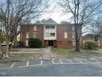 Three-story brick apartment building with mature trees and marked parking spaces at 3520 Ivy Commons Dr # 302, Raleigh, NC 27606