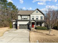 Inviting two-story home boasts a three-car garage and a charming red front door at 3916 Bostwyck Dr, Fuquay Varina, NC 27526