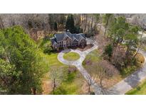 Aerial view of a brick home with a circular driveway surrounded by lush greenery and mature trees at 400 Tharps Ln, Raleigh, NC 27614
