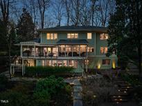 Back exterior of a two-story home with a deck, patio, and lush landscaping at dusk at 402 Westwood Dr, Chapel Hill, NC 27516