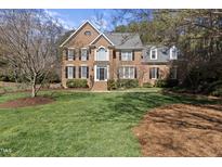 Beautiful two-story brick home with a well-manicured lawn and mature trees at 405 Tharps Ln, Raleigh, NC 27614