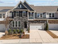 Beautiful townhome with a stone facade, two-car garage, and well-maintained landscaping at 8620 Secreto Dr, Raleigh, NC 27606