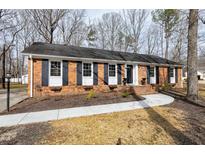 Charming brick home featuring black shutters, a well-manicured lawn, and a curved walkway leading to the front door at 1315 Shady Ln, Durham, NC 27712
