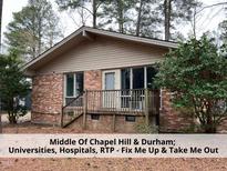 Charming brick single-story home featuring a quaint front porch and mature trees at 134 Weaver Dairy Rd, Chapel Hill, NC 27514