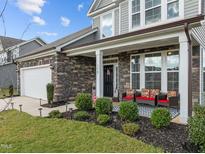 Charming home featuring a stone facade, covered porch with seating, a well-manicured lawn and a 2-car garage at 190 Hickory Run Ln, Franklinton, NC 27525