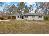 Charming single-story home with a white exterior and a spacious front yard surrounded by mature trees at 2013 Dartmouth Dr, Durham, NC 27705