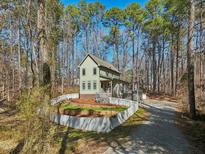 Charming home featuring a quaint front yard, gravel driveway and mature tree surround at 2431 Winburn Ave, Durham, NC 27704