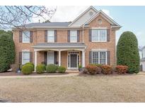 Traditional brick two-story home featuring well-manicured landscaping and a covered front porch at 302 Millsford Hill Pl, Cary, NC 27518