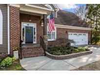 Charming brick home featuring a manicured front yard and welcoming entrance with an American flag at 3116 Kensington Pl, Burlington, NC 27215