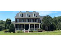 Charming brick home featuring a covered front porch, manicured lawn, and mature landscaping at 3732 Sparrow Pond Ln, Raleigh, NC 27606