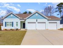 Charming, light-blue house with well-maintained lawn and a three car garage on a concrete driveway at 412 Kavanaugh Rd, Wake Forest, NC 27587