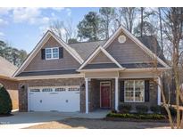 Charming brick home with a two-car garage, dormer windows, and a welcoming red front door with flower wreath at 430 Easy Wind Ln, Garner, NC 27529