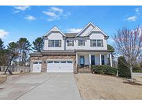 Charming two-story home featuring a stone and white siding, complemented by a well-manicured lawn at 4913 Sunset Stream Dr, Fuquay Varina, NC 27526