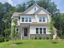 Beautiful two-story home featuring stone accents, white siding, and a well-manicured front lawn at 664 The Parks Dr, Pittsboro, NC 27312