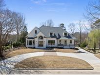 Beautiful home featuring a circular driveway, lush landscaping, and a covered front porch at 7217 Manor Oaks Dr, Raleigh, NC 27615