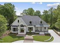Beautiful white brick home with a large arched entryway and manicured lawn, surrounded by mature trees at 7217 Manor Oaks Dr, Raleigh, NC 27615