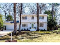 Charming two-story home with white painted brick, mature trees and a well-manicured lawn at 7416 Fiesta Way, Raleigh, NC 27615