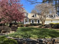 Charming home featuring manicured lawn, beautiful shrubs, neutral siding, white trim, and dormer windows at 8 Bryncastle Ct, Durham, NC 27707