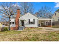 Charming exterior of home featuring awnings, a brick chimney, a covered carport, and manicured landscaping at 910 Bellvue St, Burlington, NC 27217