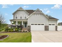 Charming two-story home featuring a manicured lawn, inviting porch, and three-car garage at 1001 Peterson Ridge Rd, Fuquay Varina, NC 27526