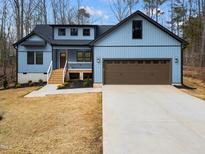 Charming blue two-story home with a brown garage door and newly landscaped front yard at 1423 Sagamore Dr, Louisburg, NC 27549