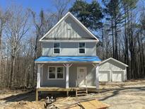 Two-story home with a front porch and a detached two-car garage, surrounded by trees at 1448B Maplewood Dr, Durham, NC 27704