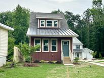 Charming two-story home with a modern metal roof, landscaped yard, and a welcoming entrance at 1448C Maplewood Dr, Durham, NC 27704