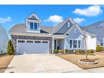 Charming two-story home with stone accents, light blue siding, a well-manicured lawn, and a two car garage at 163 Auburn Village Blvd, Raleigh, NC 27610