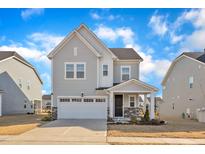 Charming gray two-story home featuring stone accents, a two-car garage, and beautifully landscaped front yard at 1776 Golden Honey Dr, Wake Forest, NC 27587