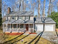 Charming two-story home featuring a welcoming front porch, a two-car garage, and mature trees at 306 Northcliff Dr, Durham, NC 27712