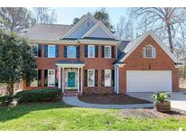 Charming brick home with a two-car garage, black shutters, and a well-maintained lawn at 521 Lyndenbury Dr, Apex, NC 27502