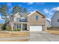 Charming two-story home featuring a brick and vinyl exterior, attached two-car garage, and well-manicured lawn at 672 Millers Mark Ave, Wake Forest, NC 27587