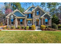 Charming home featuring a stone and brick facade, complemented by lush landscaping and a well-manicured lawn at 805 Clausun Dr, Durham, NC 27713