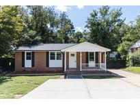 Single-story brick home with a well-manicured lawn, covered porch, and driveway at 852 Newcombe Rd, Raleigh, NC 27610
