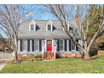Charming two-story home with a red front door and dormer windows, nestled in a well-manicured lawn and mature trees at 8617 Canoe Ct, Raleigh, NC 27615