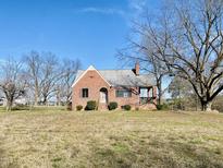 Charming one-story brick home with a unique design and well-maintained lawn under a clear blue sky at 1006 Stallings Rd, Durham, NC 27703