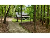Charming brick home with a welcoming front porch surrounded by lush trees and a long, winding driveway at 1013 Traders Trl, Wake Forest, NC 27587