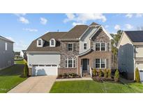 Beautiful exterior elevation showcases a two-car garage, brickwork, and manicured landscaping at 112 Ava Ct, Holly Springs, NC 27540