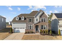 Charming two-story home featuring a stone and vinyl exterior, well-manicured lawn, and a two-car garage at 112 Ava Ct, Holly Springs, NC 27540