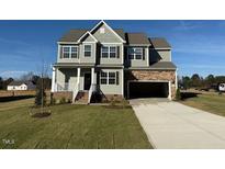 Charming two-story home features a stone-accented garage and well-manicured lawn at 11412 International Dr, Middlesex, NC 27557