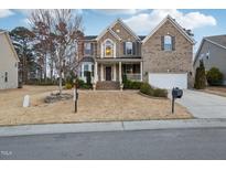 Charming two-story brick home with manicured lawn, attached garage, and inviting front porch at 127 Plano Dr, Durham, NC 27703
